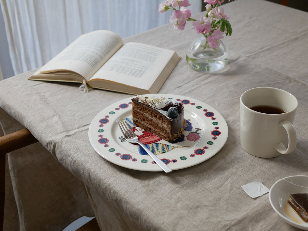 イッタラのタイカサトプレートがテーブルクロスの上に並べられた食卓の様子。磁器製の複数サイズのプレートが配置されています。