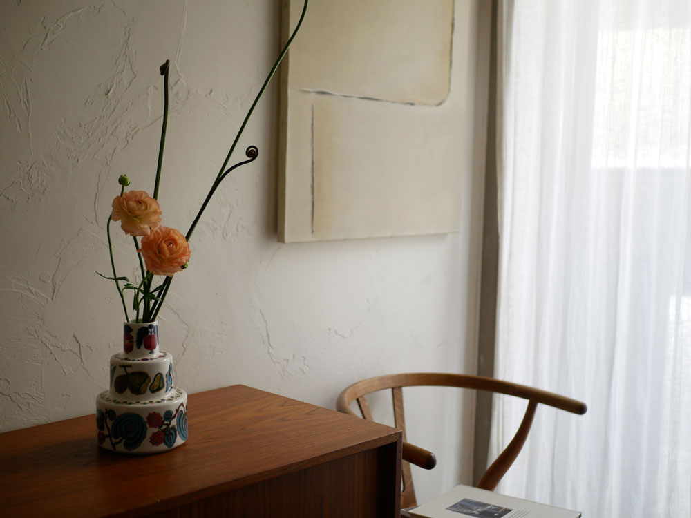 イッタラのタイカサトベースが室内のテーブルに配置され、周囲に照明や家具、観葉植物が調和したインテリアデザインのリビングルーム