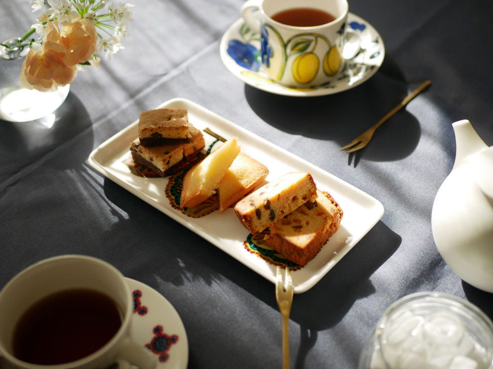 イッタラのタイカ サト スクエアおよびレクタングルプレートにケーキやデザートが盛られた食卓の様子