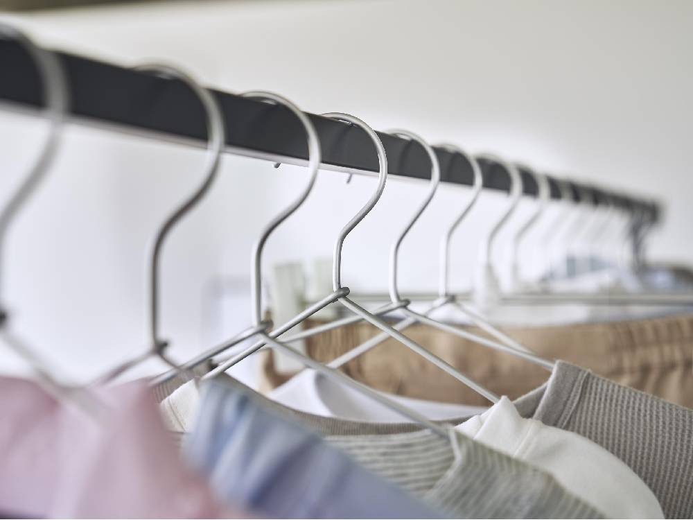 シルバー色の折りたたみ可能な室内物干しスタンドにハンガーが掛けられている様子