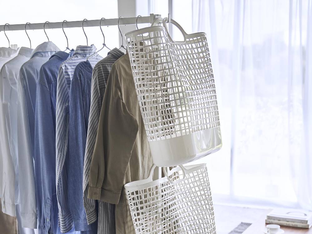 スチール製の【tower/タワー】折り畳み室内物干し。複数のハンガーとバスケットが配置され、シルバーのパーツが際立つデザイン。