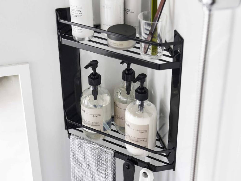 マグネット式2段バスルームコーナーラックがスチール製の壁面に設置され、棚とフックに洗面用具やボトルが整然と配置されている様子