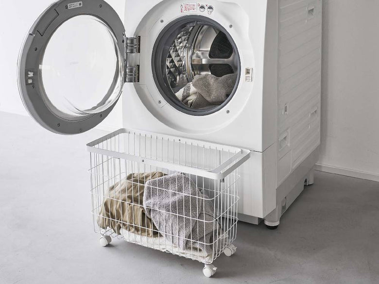 洗濯室にキャスター付きスチール製ランドリーバスケットが洗濯機と乾燥機の横に置かれている様子