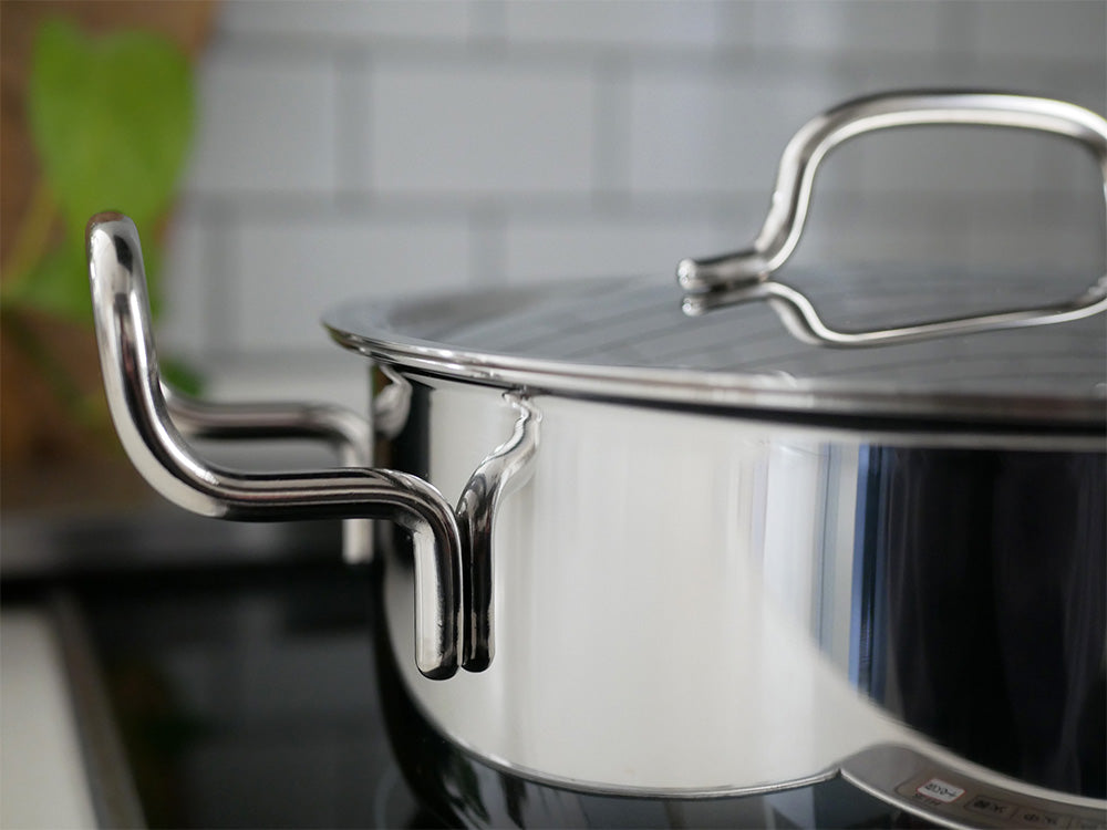 ステンレスとアルミニウム製の蓋付き鍋がキッチンのカウンターに置かれている