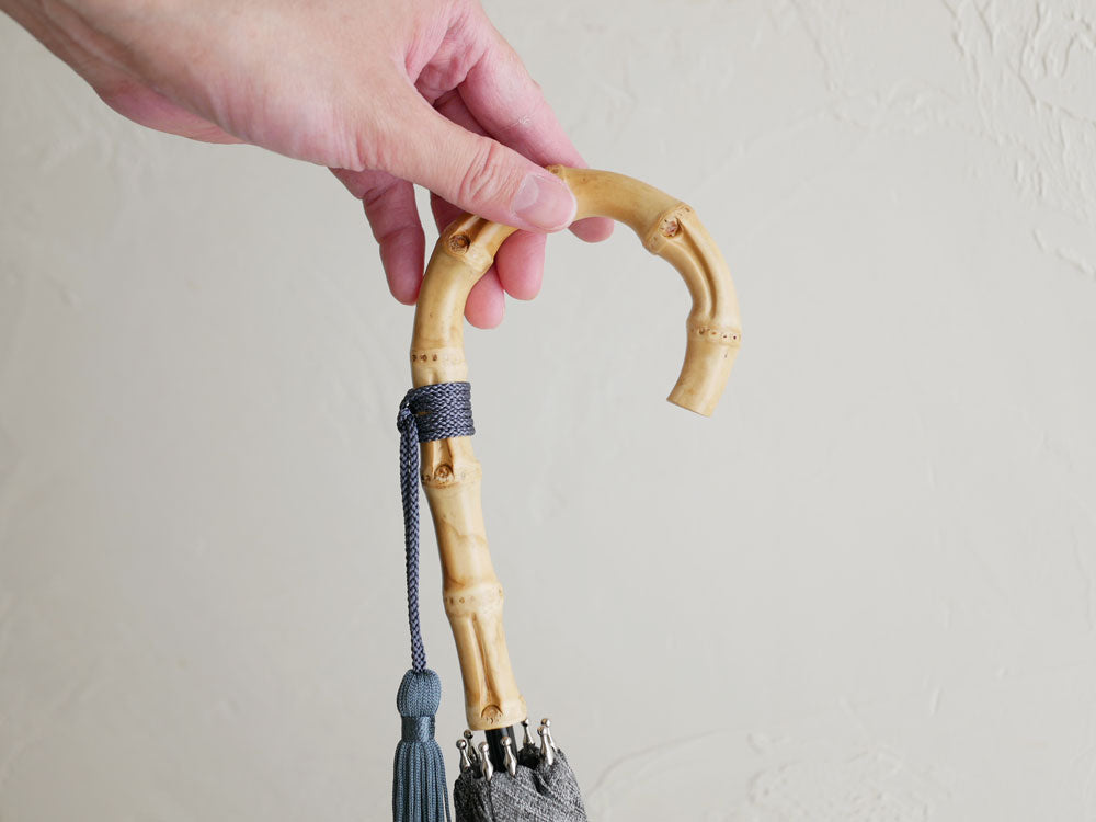 ビコーズのプレーンカラー傘。ロープや糸、結び目があしらわれたデザインで、バンブーハンドルと鉄製の骨を備えたポリエステル100％の傘。