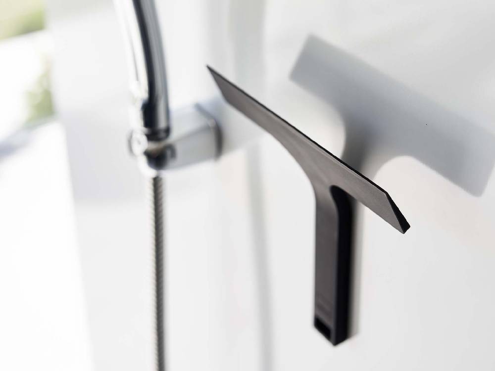 シルバーのアルミハンドルを持つマグネット水切りワイパーがスチール壁面に取り付けられている様子