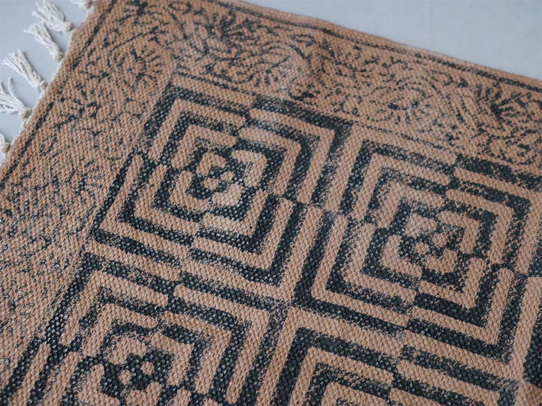 アデペシュ製マニエールコットンラグ。茶色の対称的な模様が特徴的なデザインカーペットが床に敷かれています。