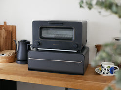 キッチンカウンターに設置された【UtaU】カウンタードロワーのピュアホワイトモデル。開いた引き出しにはトースターや小型家電が整理整頓されている様子を示しています