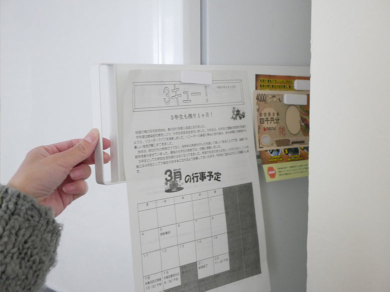 マグネット式スライドスチールパネルが冷蔵庫横に取り付けられ、紙製品やオフィス用品を収納して整理整頓する様子