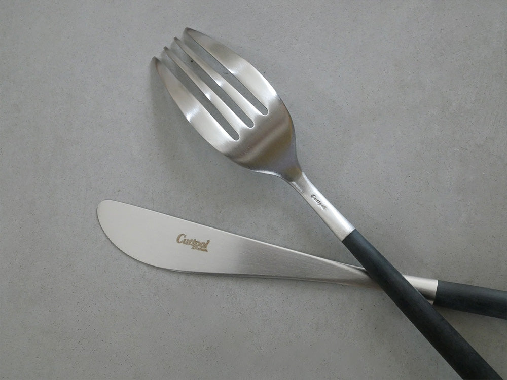 クチポールのMIOカトラリーセット。ブラックとアイボリーゴールドのフォーク、スプーン、ナイフが整然と並んでいる