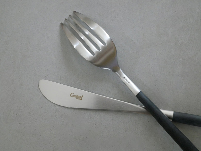 クチポールのMIOカトラリーセット。ブラックとアイボリーゴールドのフォーク、スプーン、ナイフが整然と並んでいる