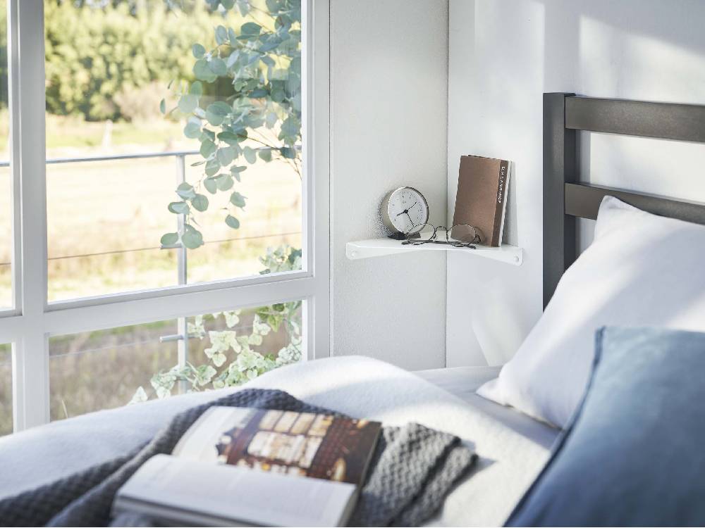 ベッドルームのインテリアに配置された【tower】石こうボード対応コーナーシェルフとベッド、寝具、家具が調和する空間