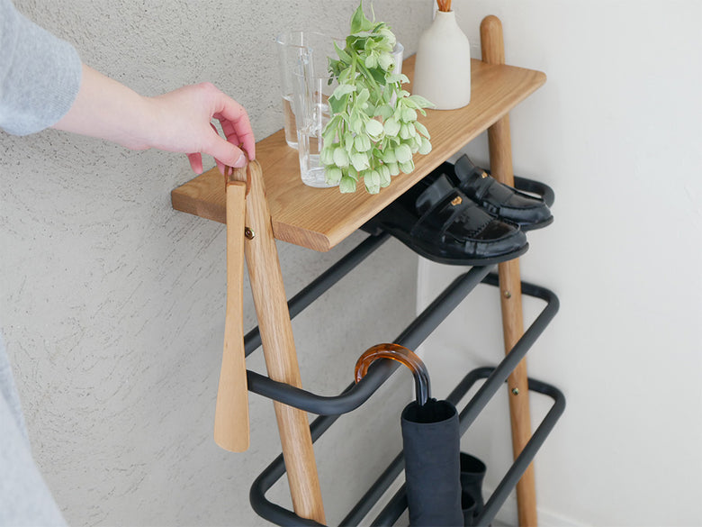 オーク無垢材とスチール製の立て掛けシューズラック、複数の棚が備えられたデザイン
