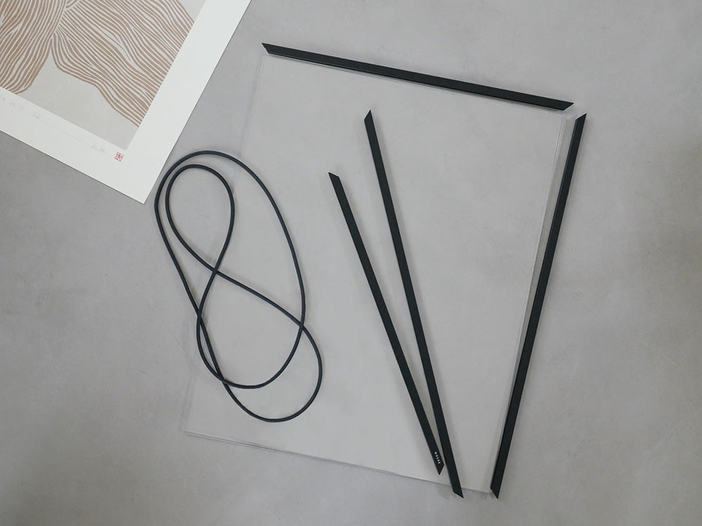 シルバーのMOEBE FRAMEがオフィス用品やカーボンファイバー製の電気ケーブル、文房具と共に配置された静物写真