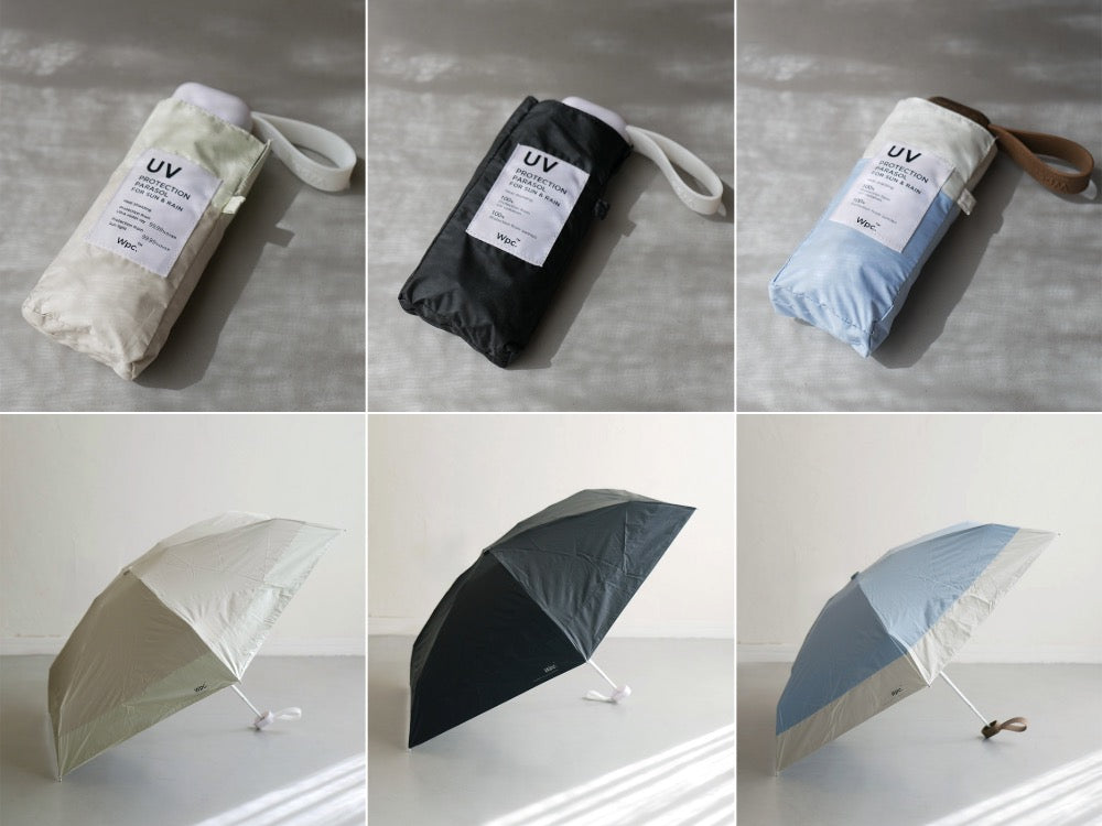 ダブリュピーシーのスマホサイズ折りたたみ傘が紙やリネンと共に配置されている様子