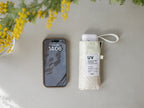 Wpc.ダブリュピーシーのスマホサイズ折りたたみ傘。黒色のポリエステル生地で完全遮光・UVカット機能を備え、軽量210gでコンパクトに収納可能な携帯用デザイン。