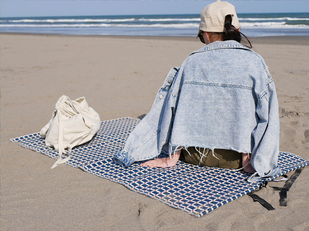 砂浜に広げられたシセイの洗えるレジャーマットとビーチタオル