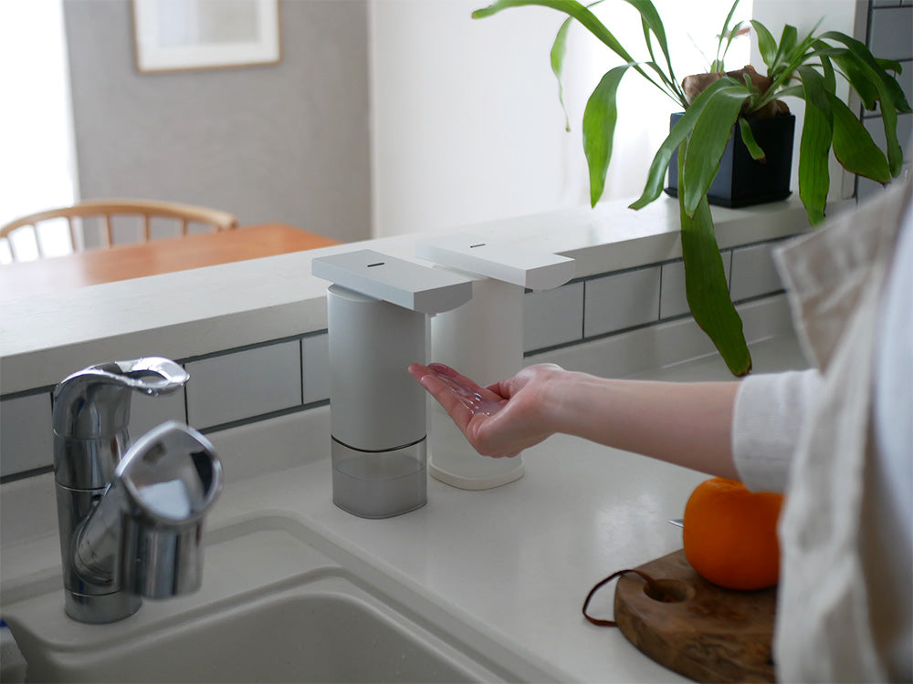 バスルームのシンクカウンターに置かれたプラスマイナスゼロオートディスペンサーと観葉植物