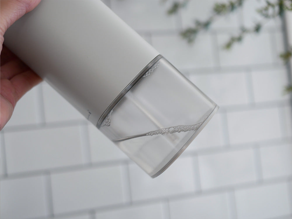 銀色の円柱形オートディスペンサーがハイボールグラスに水を注いでいる様子