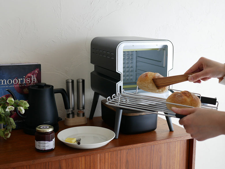 レコルトのスライドラックトースターがキッチンに置かれている様子。クリームホワイトとブラックのデザインで、スチールとガラス素材を使用した家庭用小型電化製品