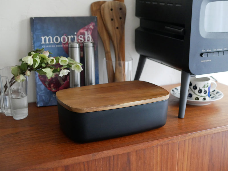 レコルトのクリームホワイトブレッドケースが木製デスクの上に置かれ、電子機器やオフィス用品と共に配置されている様子