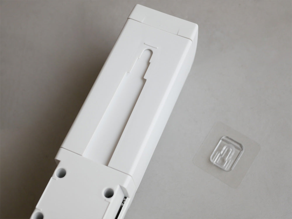 リッチェル製のプラスチック製シールフックディスペンサーが光沢のある平らな壁面に取り付けられている