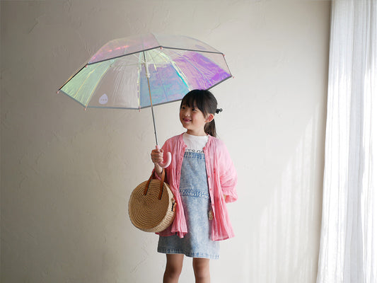 笑顔の幼児がピンクのシャイニーキッズアンブレラをさしている写真