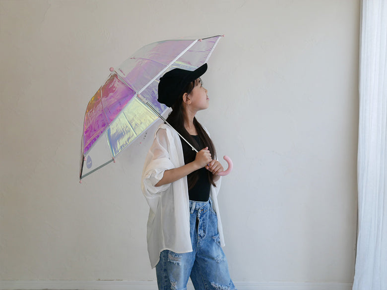 シャイニーなピンク色の子供用アンブレラを持ち、デニムとレギンスでスタイリングされたモデルのファッション写真