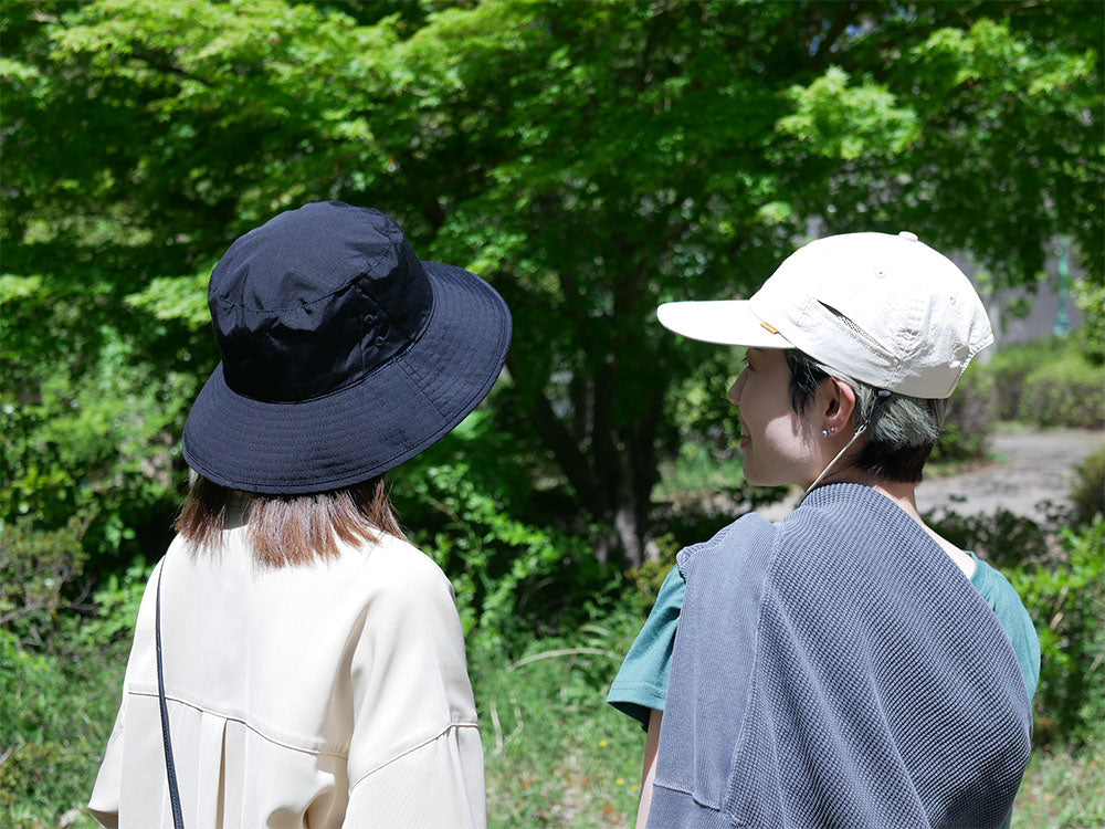 撥水加工が施された黒色フェドラスタイルの日傘ハット。調節可能なサイズとデオドラントタグが特徴で、夏のアウトドアに最適です。