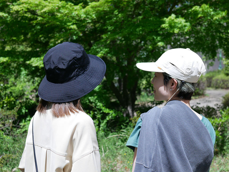撥水加工が施された黒色フェドラスタイルの日傘ハット。調節可能なサイズとデオドラントタグが特徴で、夏のアウトドアに最適です。