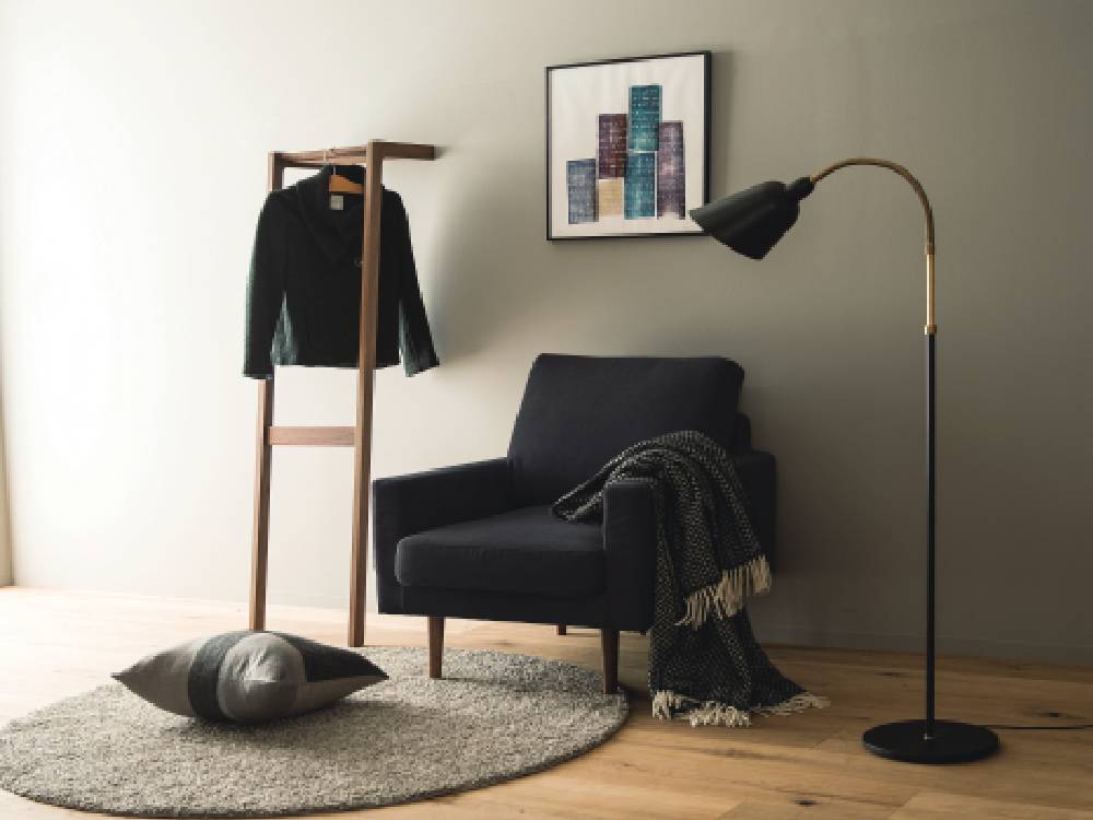 リビングルームに配置された高野木工のLEOソファ、ブラウンのランプと観葉植物が調和する木製フローリングとカーテンが特徴の空間