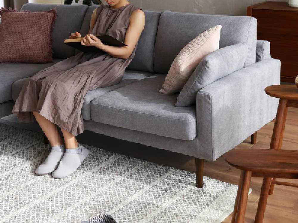 高野木工のLEOソファがリビングルームに配置され、複数のクッションとピローで快適にスタイリングされている様子