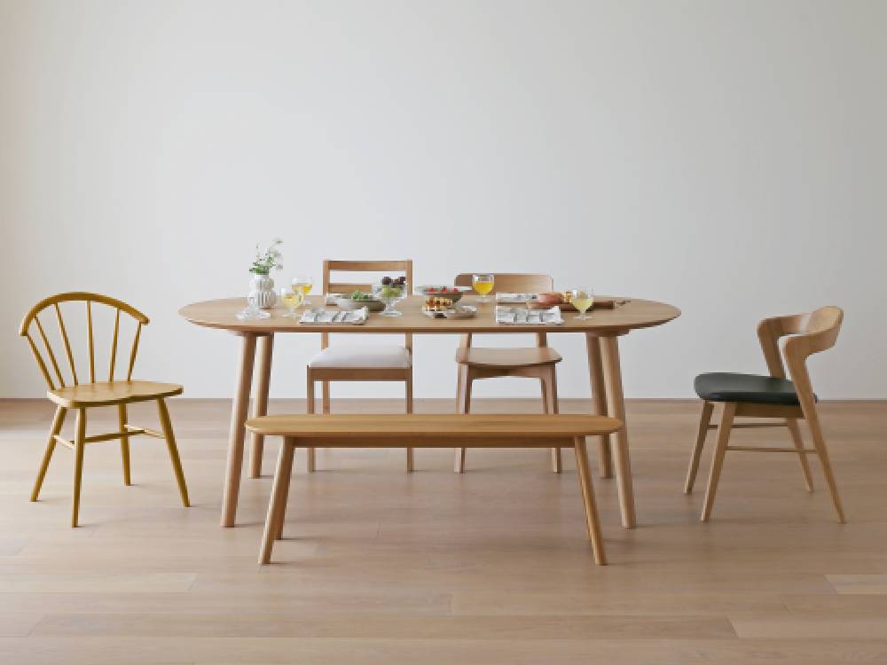 高野木工のRUBEベンチと木製テーブル、チェア、花鉢や花束が配置された屋外ダイニングスペース