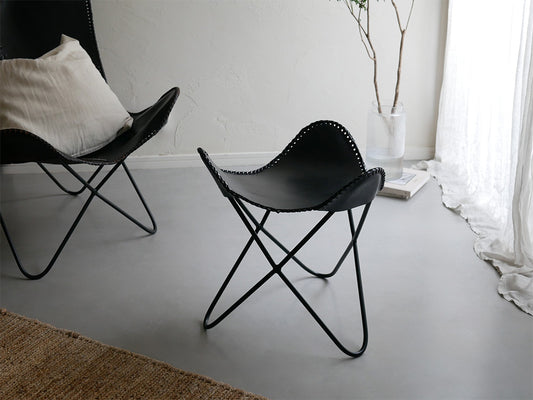 木製フロアのリビングルームに配置された、灰色のラップス製アイアンレザークラブチェア。快適なアームレスト付きでナチュラルな雰囲気を演出