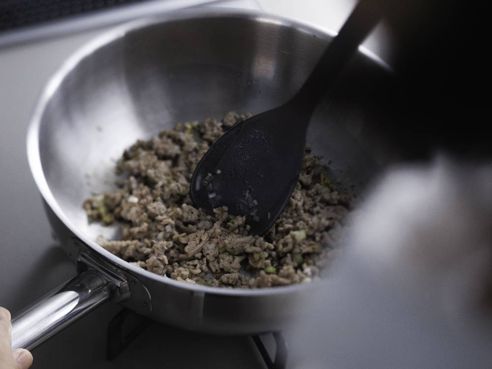 marnaのスプーンヘラがフライパンと食材とともに調理台に置かれているキッチン用品の画像