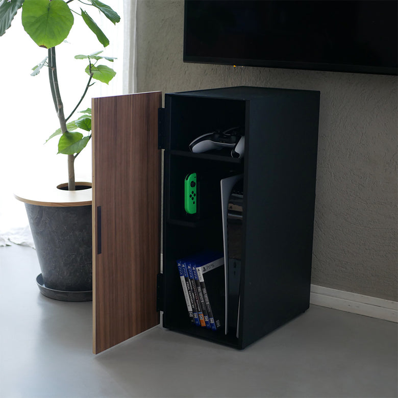 スチールと天然木を組み合わせたタワー型ゲーム機収納ラック。複数の棚に本やスピーカー、観葉植物が配置されたモダンな家具