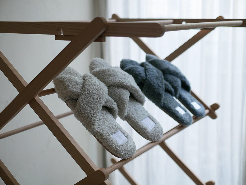 サラサデザインの抗菌防臭パイルスリッパが、自然素材のバスケットや衣類ハンガーとともにディスプレイされた洗濯用品のセット。