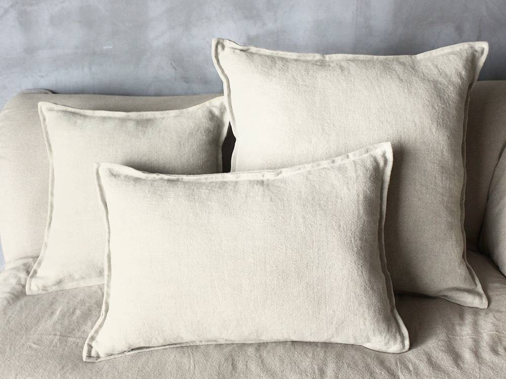 灰色のリネンソファにシルバーのベルベットクッションとランプが添えられたインテリア