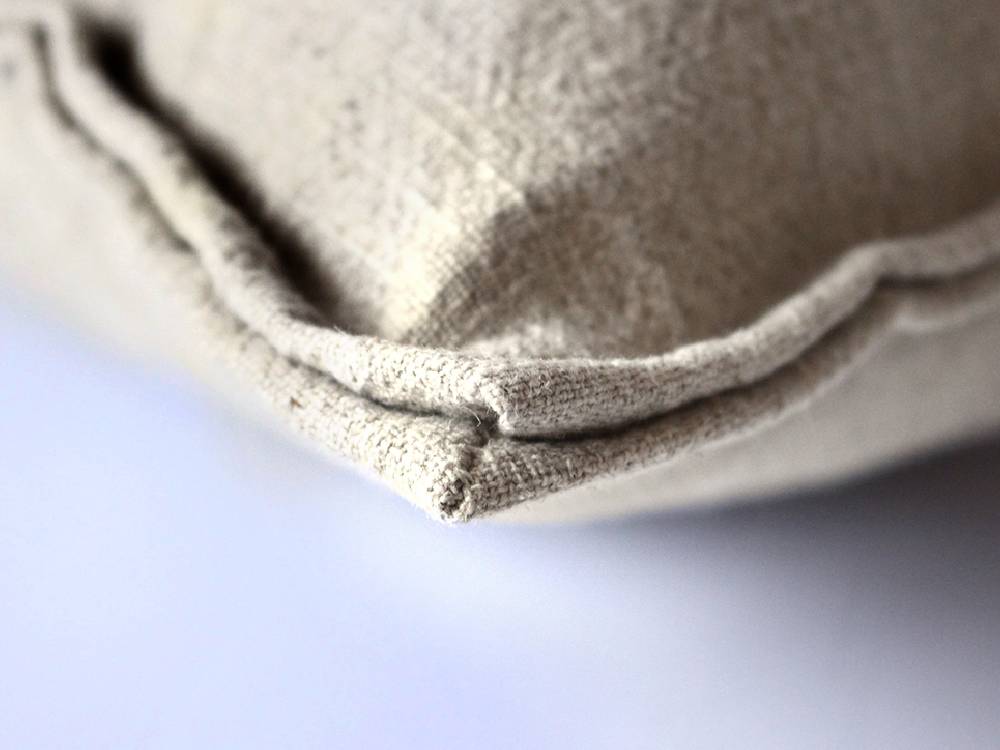 グレーのリネン製クッションが並べられたアデペシュのフレンチリネンソファ