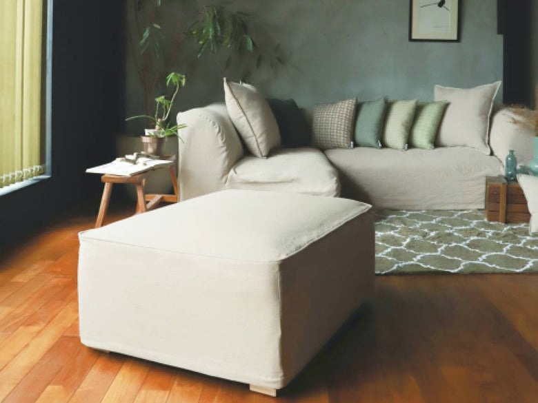 リビングルームに設置されたアデペシュのグレーのフレンチリネンソファとクッション、木製フローリング