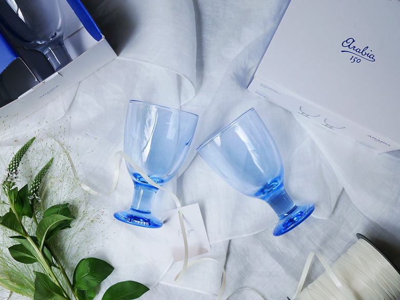 アラビア VERNA ユニバーサル グラスペア2個、青色の無鉛ガラス製ワイングラスがテーブル上に並べられている画像