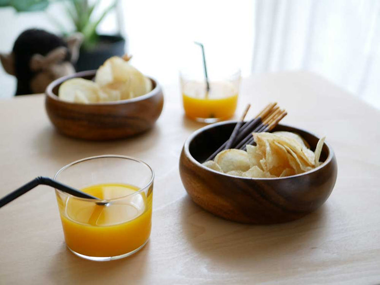 アカシア木製の食器に盛られたオレンジジュースとフルーツが並んだテーブルの様子