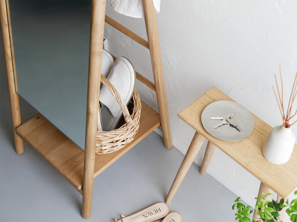 オーク材を使用した収納付きスタンドミラーと花鉢、籠が配置されたナチュラルな室内インテリア