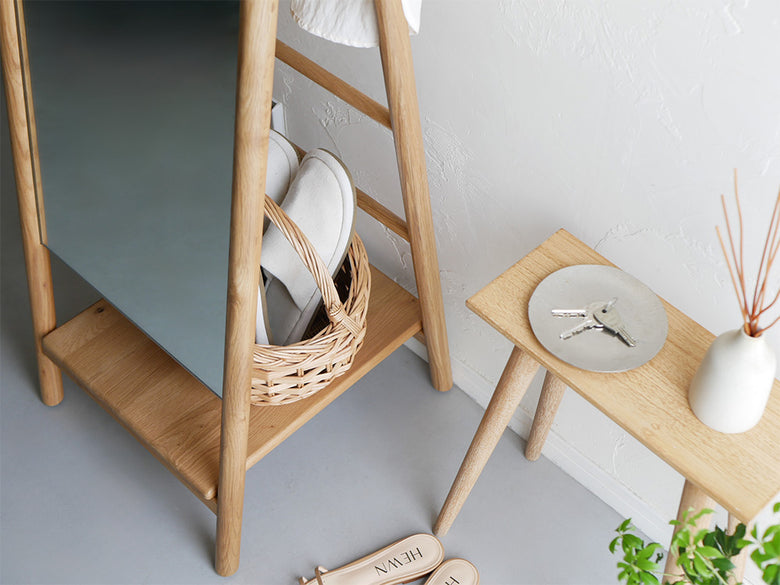 オーク材を使用した収納付きスタンドミラーと花鉢、籠が配置されたナチュラルな室内インテリア