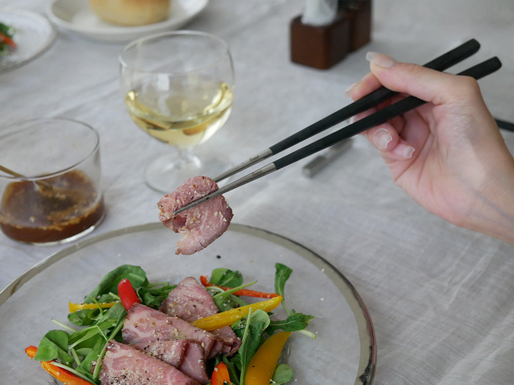 クチポールのKUBEチョップスティックと箸置きが、牛肉料理と共にテーブルに美しく配置されている様子