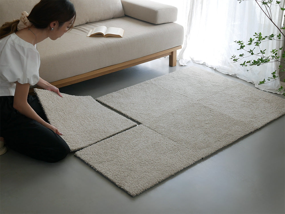 リビングルームの木製フローリングに敷かれた6枚セットの洗えるユニットラグ。自然素材で家具と調和したナチュラルなカーペット