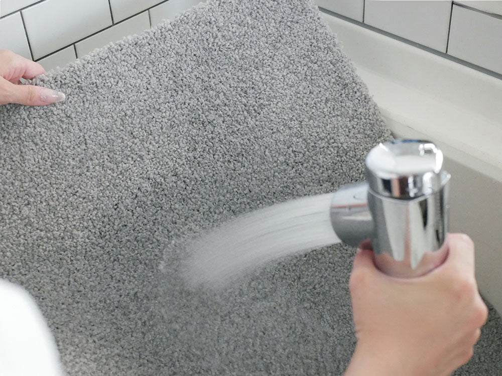 シルバー製の洗面台と蛇口、タオルや家庭用清掃用品が配置されたバスルーム