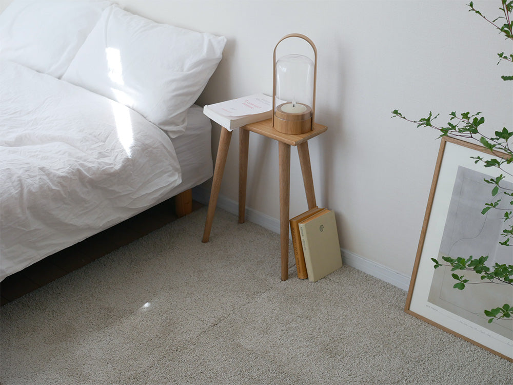 木製床に6枚セットの洗えるユニットラグが敷かれ、スツールとランプが配置された室内の様子