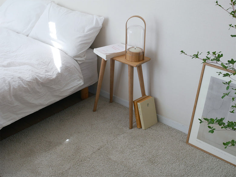 木製床に6枚セットの洗えるユニットラグが敷かれ、スツールとランプが配置された室内の様子