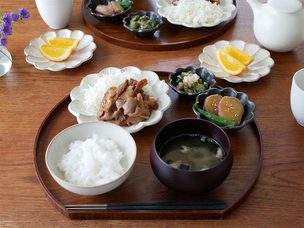 「TOJIKITONYA リンカ」シリーズの磁器製花皿とプレートに新鮮な野菜料理が美しく盛り付けられた食卓のシーン